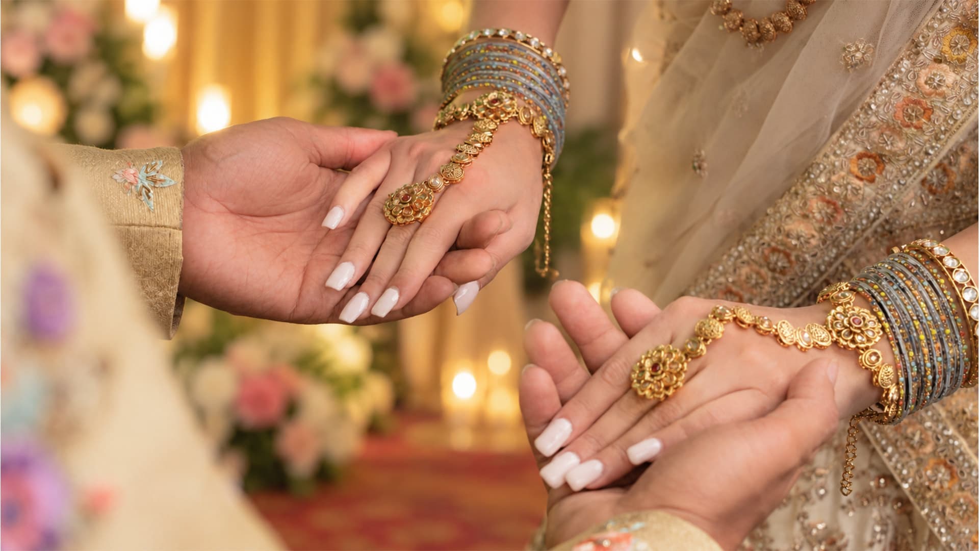A couple's hands held together, hers in bridal jewellery